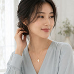 woman wearing a gold teardrop necklace