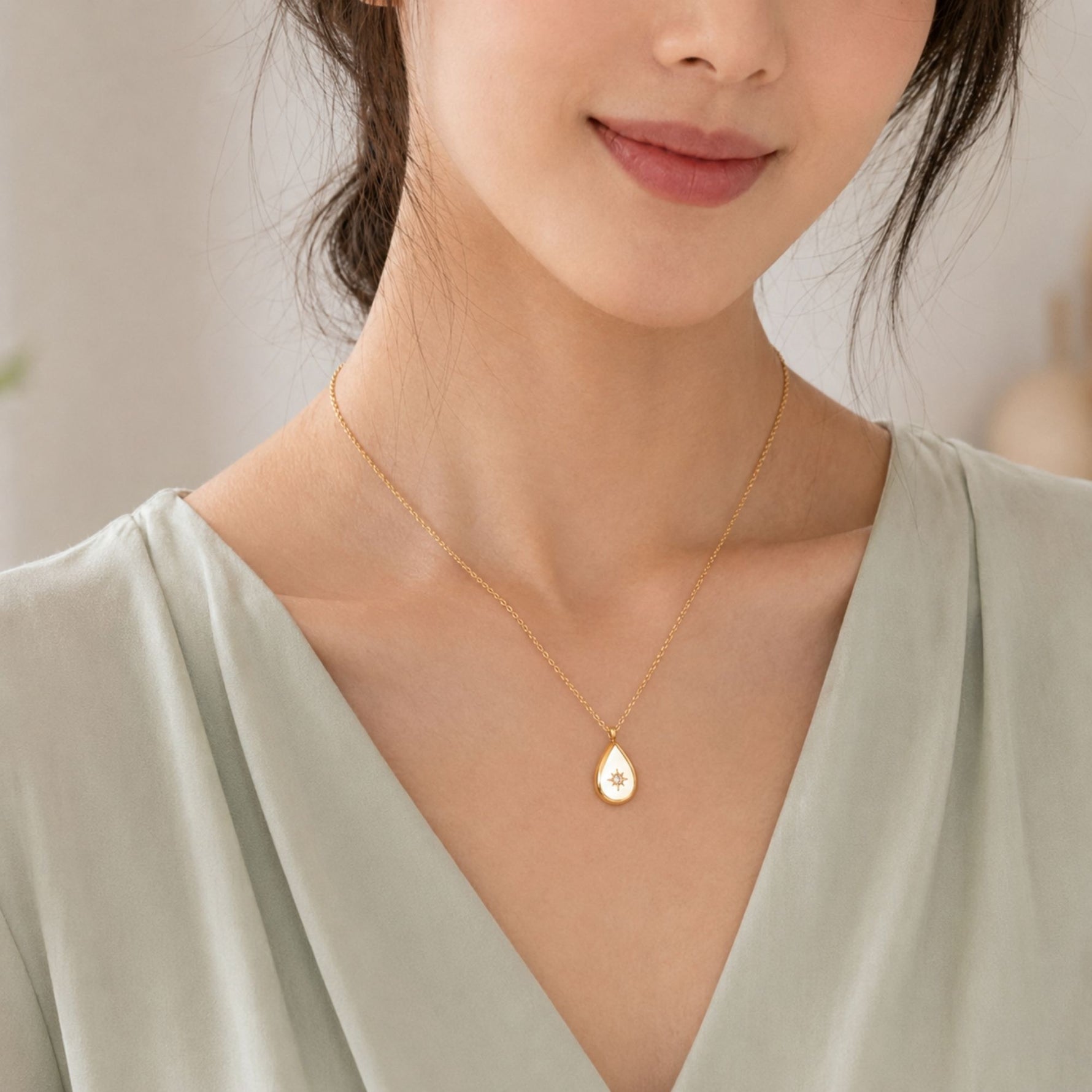woman wearing a gold teardrop necklace